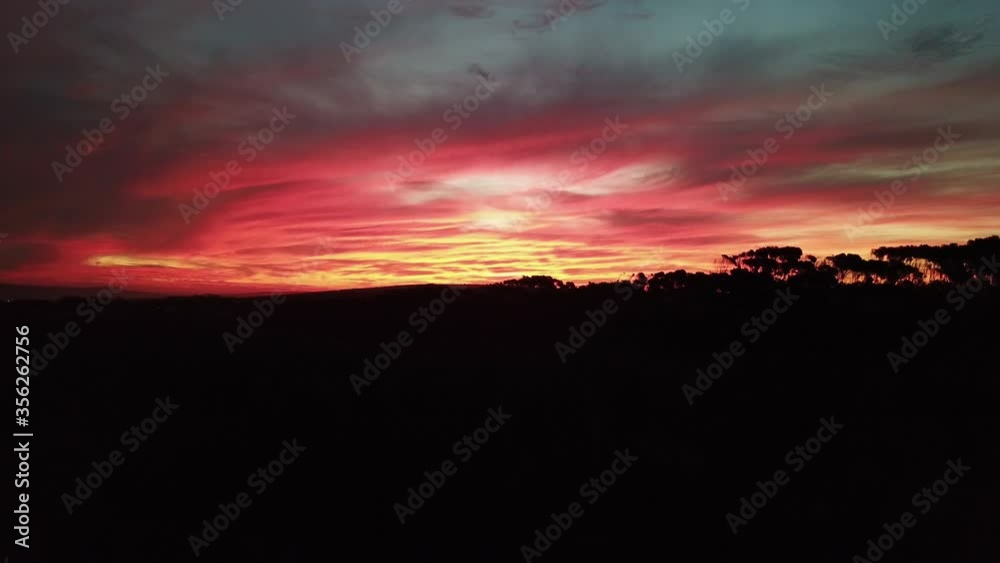 Landscape and moody sky with dark clouds and a bright red sunset Landscape and moody sky with dark clouds and a bright red sunset