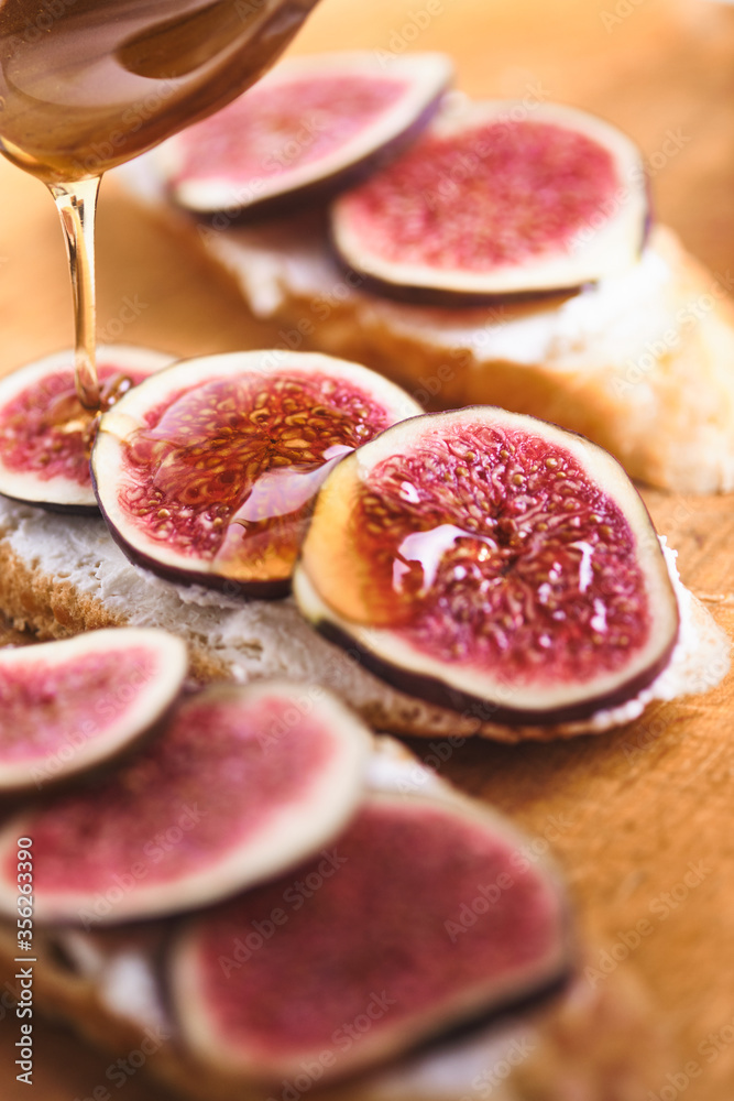 Bruschettas with figs, soft cheese and honey on a wooden board.