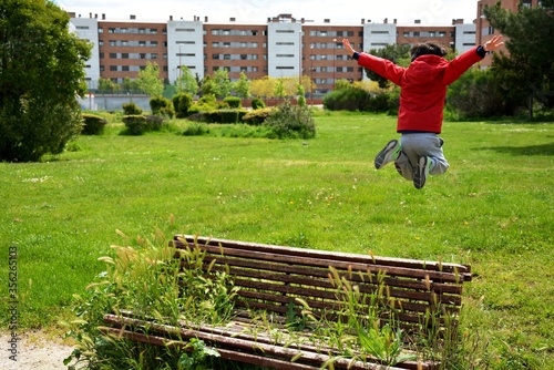young boy jumping in the park on a bench full of plants
