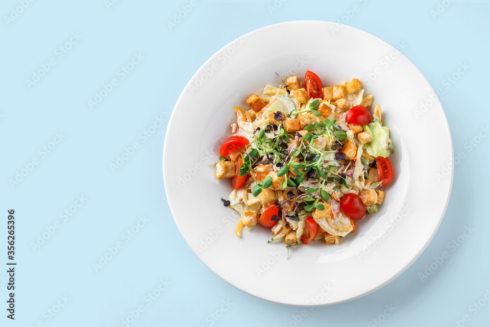 Caesar salad with lettuce, tomatoes, sprouts, croutons and sauce in plate on isolated blue background. Healthy food, vegetarian dieting, top view Caesar salad with lettuce, tomatoes, sprouts, croutons and sauce in plate on isolated blue background. Healthy food, vegetarian dieting, top view