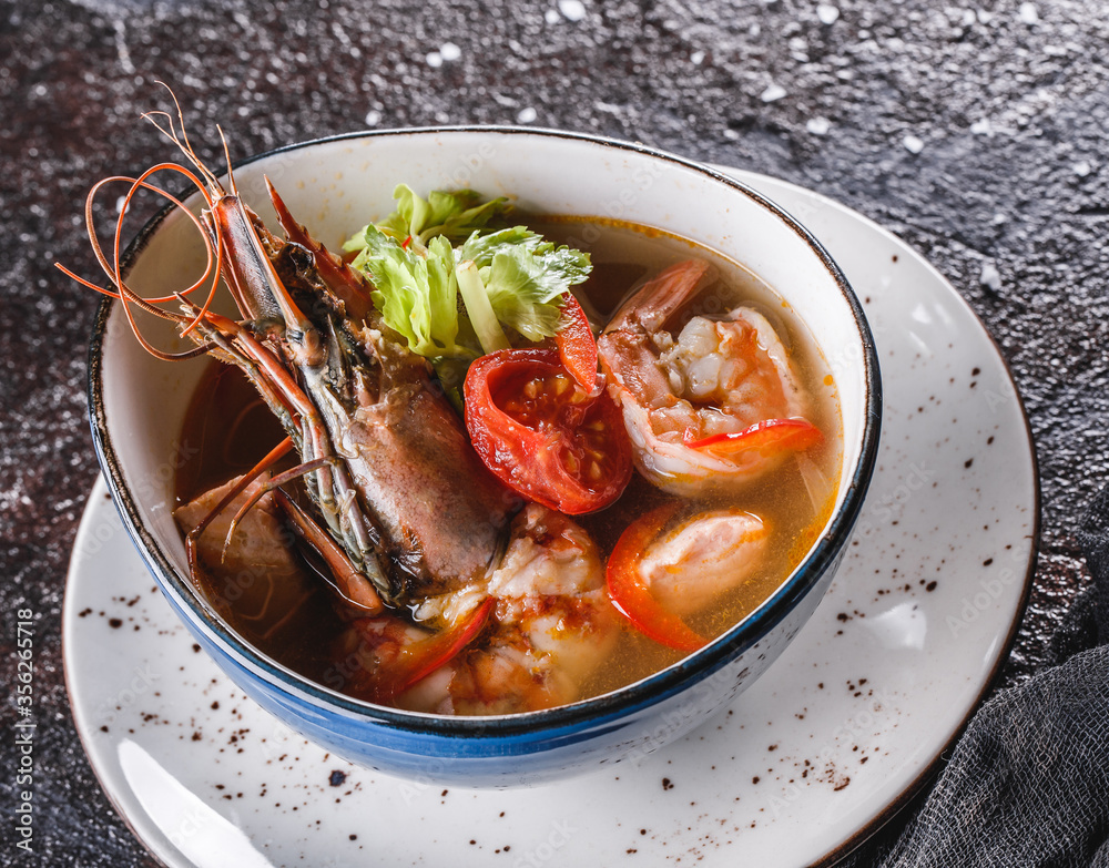 Seafood soup with langoustine, mussels, squid, fillet salmon, shrimp and celery in bowl over dark background. Healthy food, diet food, mediterranean food, closeup Seafood soup with langoustine, mussels, squid, fillet salmon, shrimp and celery in bowl over dark background. Healthy food, diet food, mediterranean food, closeup