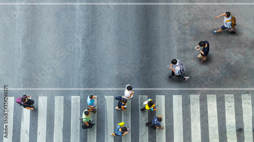 Human life in Social distance. Aerial top view with blur man with smartphone walking converse with busy city crowd move to pedestrian crosswalk photo