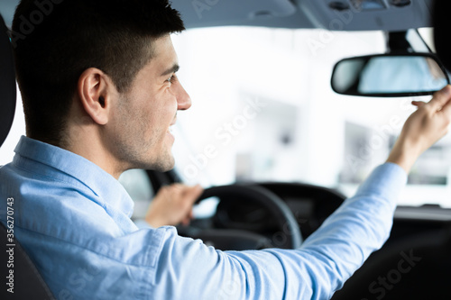 Guy Checking Rareview Mirror Sitting In Driver's Seat