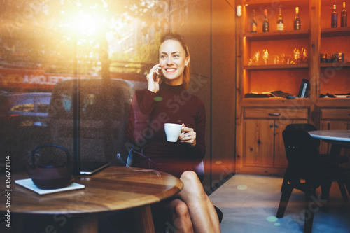 Attractive female watching video or reading business weblog in network on cell telephone