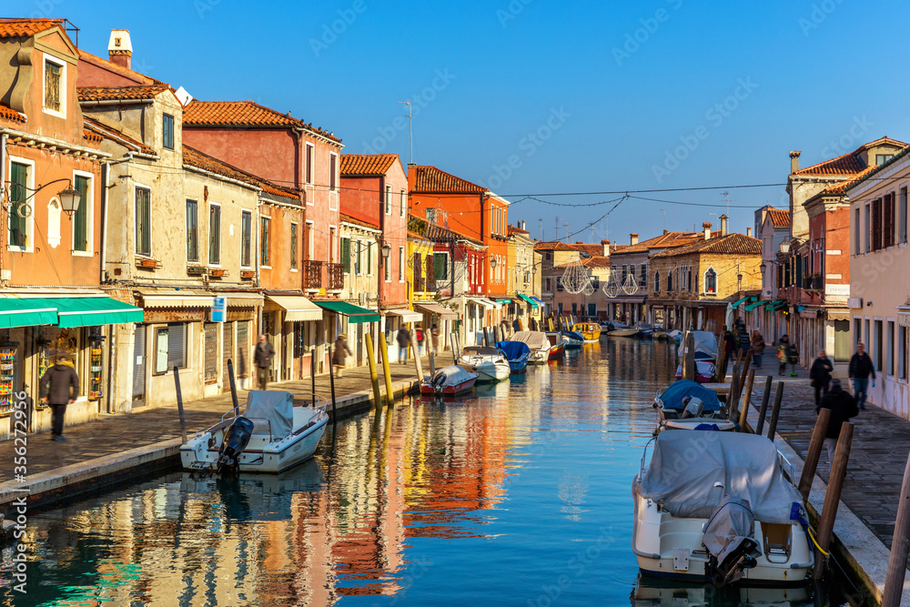 Murano glass making island, water canal, bridge, boat and traditional buildings. Venice or Venezia, Italy, Europe.