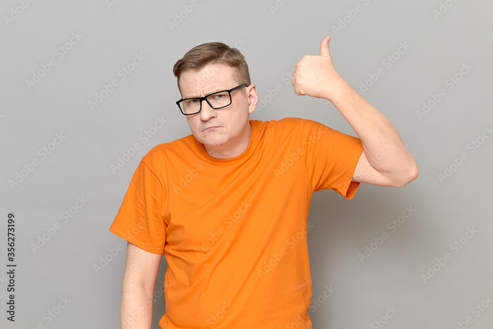Portrait of serious man raising thumb up in approval and like gesture