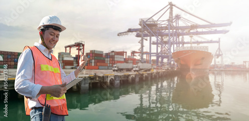 container boat and cargo pier wearhouse with Asian worker staff engineer hold tablet