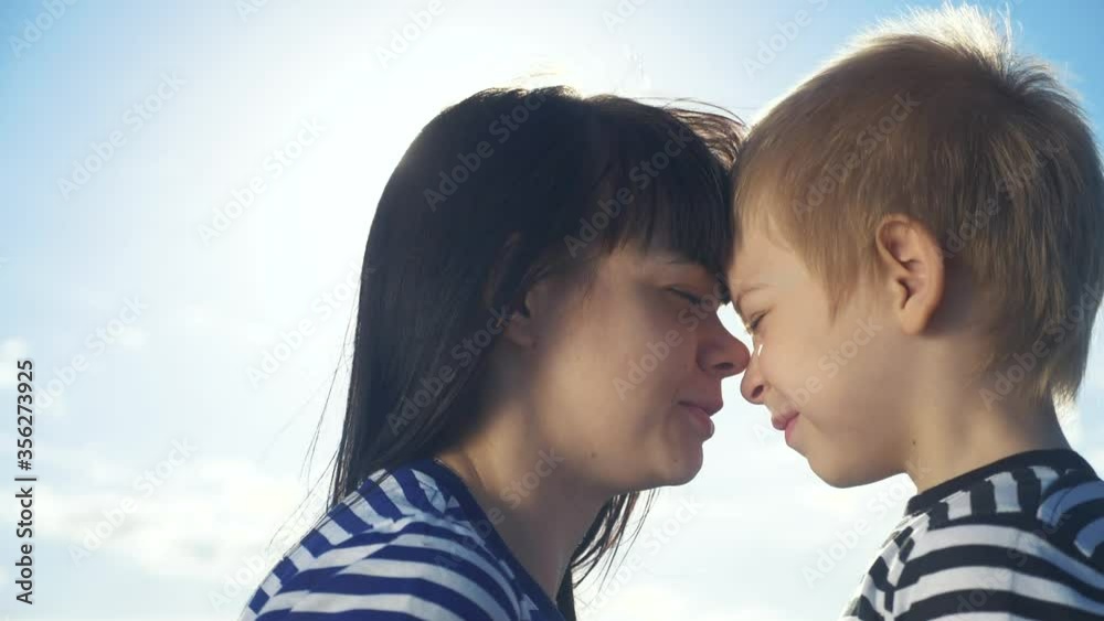 son and mom cute video concert mother's day. teamwork happy family boy kisses mother on the cheek touches his nose. parent takes care lifestyle of the child. kid and adult woman mom in the sunlight at son and mom cute video concert mother's day. teamwork happy family boy kisses mother on the cheek touches his nose. parent takes care lifestyle of the child. kid and adult woman mom in the sunlight at