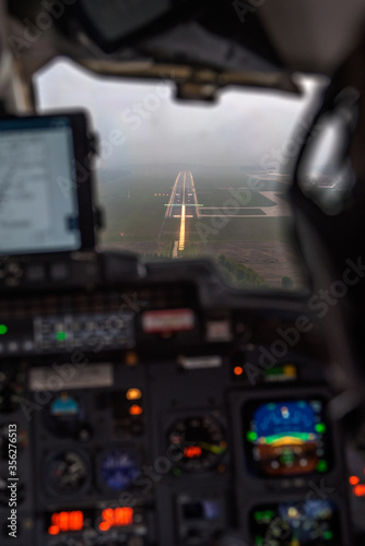 cockpit of an airplane during final approach, runway in sight. Focus on approach lights and runway. Cockpit instrumentation out of focus