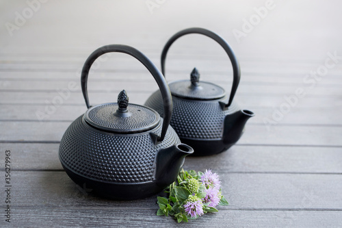 Two Black Metal Tea Pots on a light brown wooden background