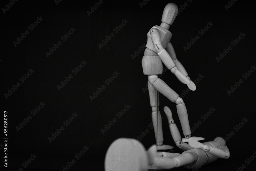wooden mannequin standing on black background stepping on wooden mannequin standing on black background stepping on