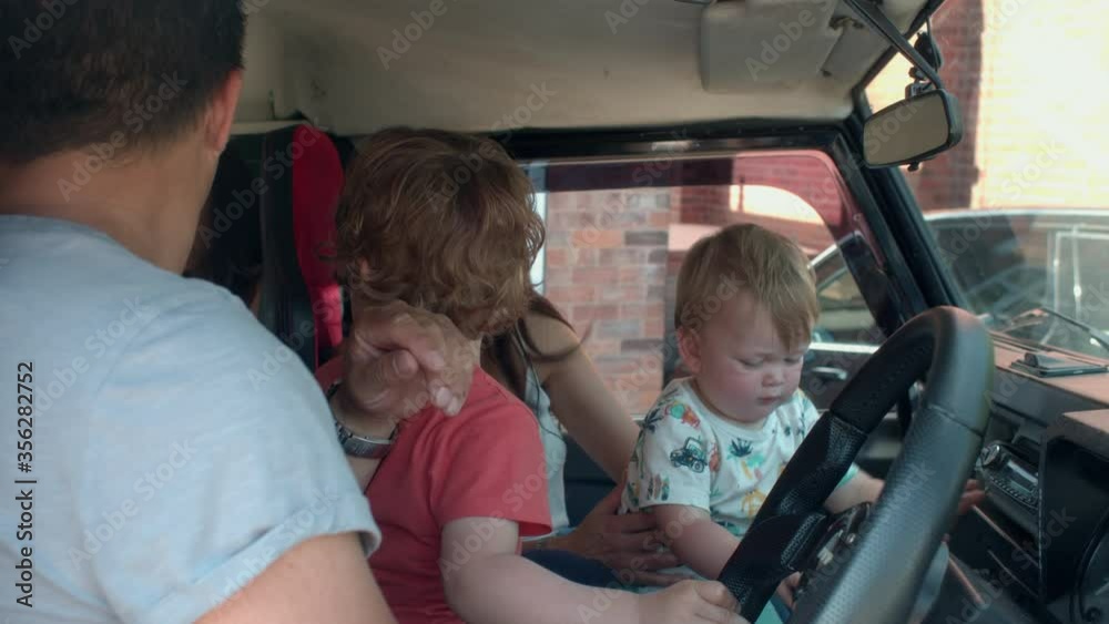 Father sitting in a car with his children.