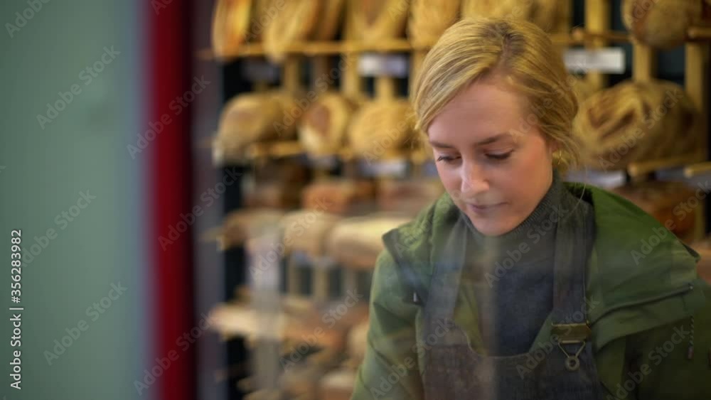Blond woman working at bakery on Norwich market, England. Blond woman working at bakery on Norwich market, England.