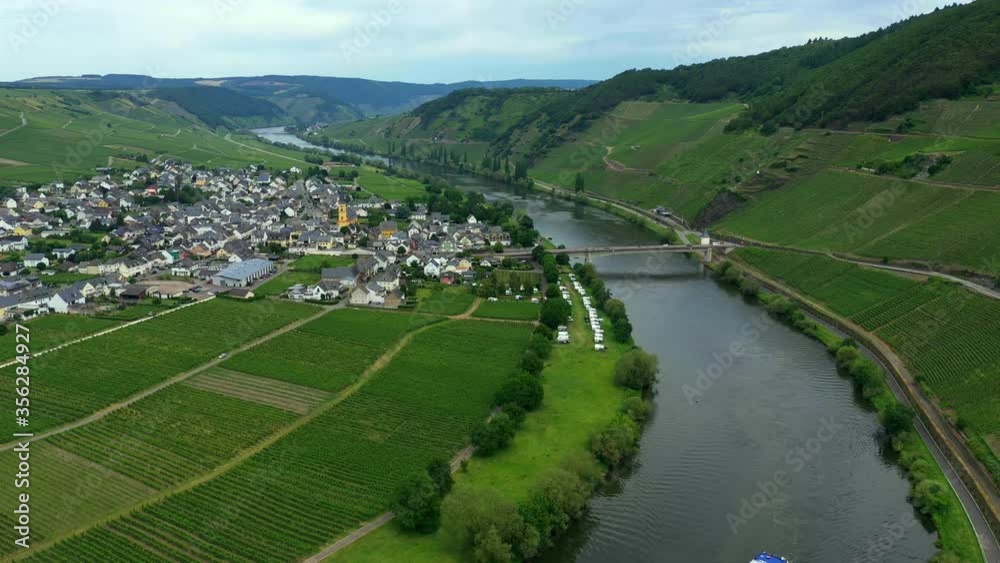 A view from high of a wide river in a green valley with a town surrounded by fields. A bridge over the river and a boat in the foreground. A view from high of a wide river in a green valley with a town surrounded by fields. A bridge over the river and a boat in the foreground.