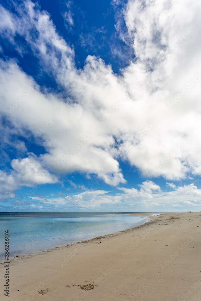 Deserted beach and white puffy clouds in blue sky