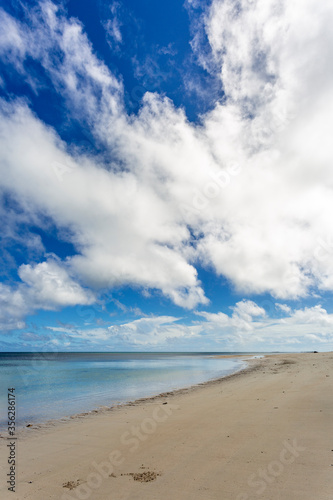 Deserted beach and white puffy clouds in blue sky