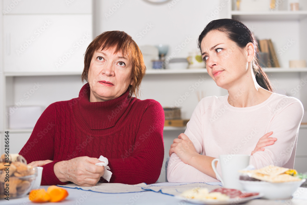 Unhappy adult female quarrel with daughter at table
