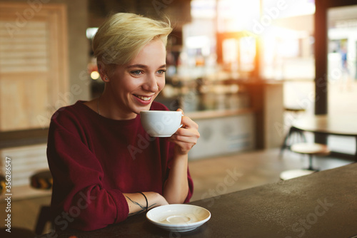 Caucasian young female enjoying cappuccino drink in coffee shop photo