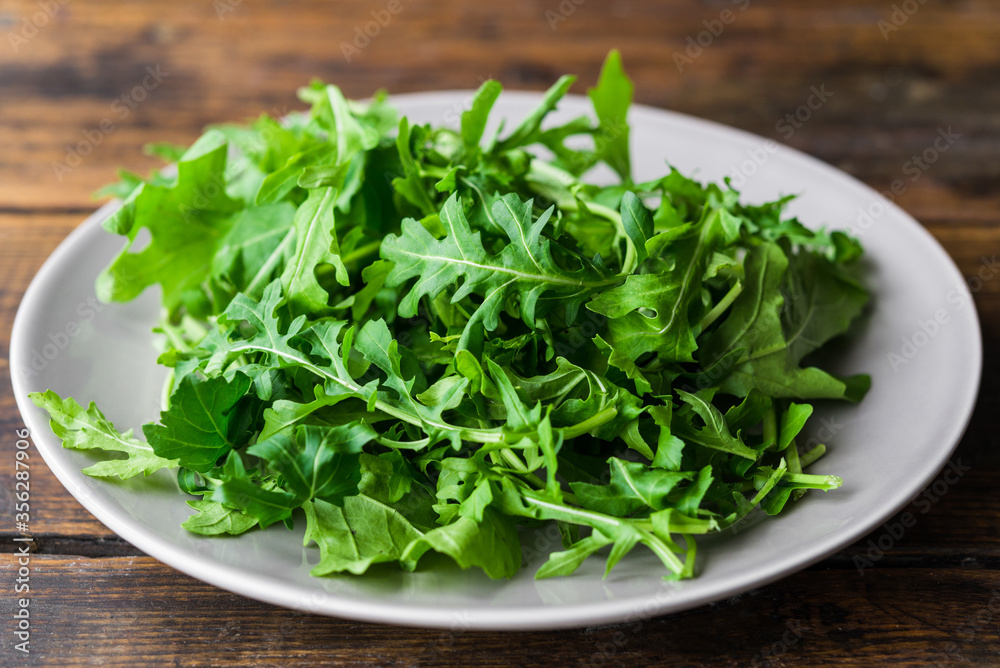 Arugula rocket salad on a plate against wooden background Arugula rocket salad on a plate against wooden background