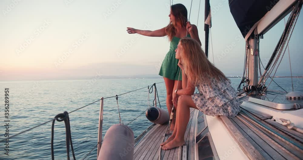 Two young women enjoying trip on a sailboat in the Ligurian Sea.
