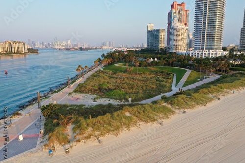 Aerial view of South Pointe Park and South Beach in Miami Beach, Florida at sunrise with Port Miami and City of Miami skyline in background.