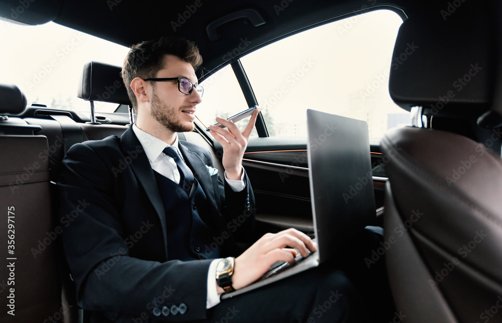 Young businessman talking on phone in taxi