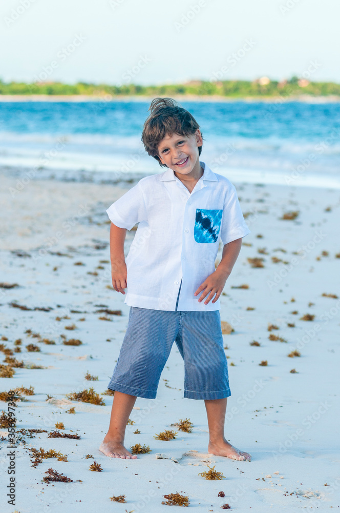 Niño con pantalones cortos y camisa blanca en playa del mar Caribe Stock  Photo | Adobe Stock