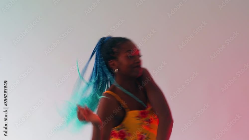 A young black girl with long turquoise plaits dancing to a rhythm, a strong beat. A young black girl with long turquoise plaits dancing to a rhythm, a strong beat.