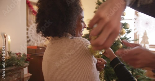 CU HANDHELD Man with son (6-7) wrapping woman with gold Christmas garland / Dinton, Wiltshire, UK photo