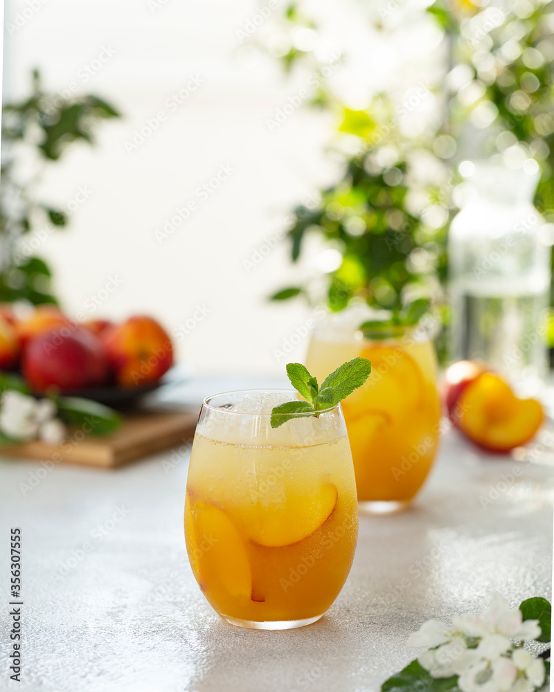 Summer cold drinks: homemade peach cocktail with ice cubes, and mint in glass. Refreshing summer homemade non-alcoholic cocktails. Selective focus Summer cold drinks: homemade peach cocktail with ice cubes, and mint in glass. Refreshing summer homemade non-alcoholic cocktails. Selective focus