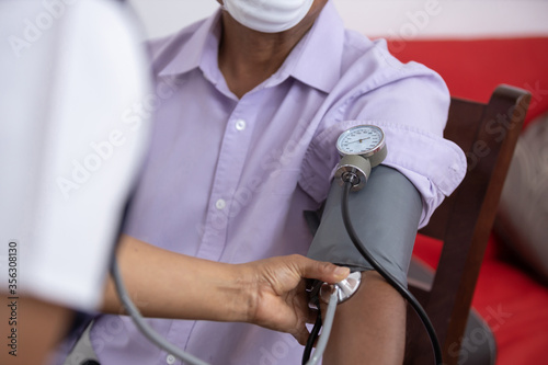 mexican nurse taking vital signs to patient wearing face mask at home photo