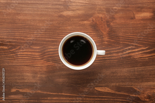 Cup of hot coffee on wooden background, top view