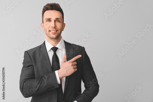 Portrait of handsome businessman showing something on grey background