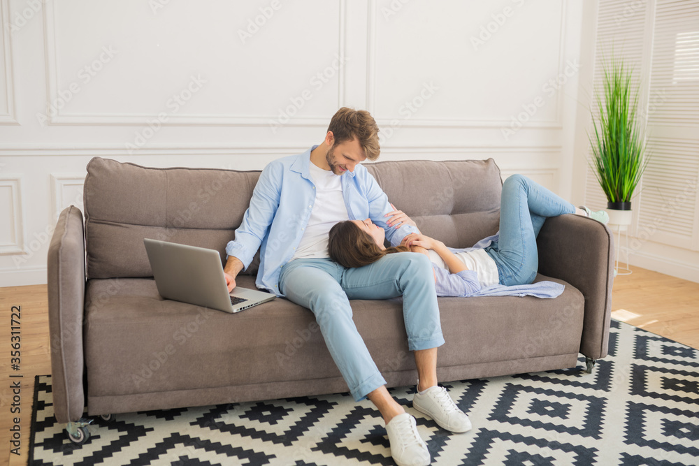 Young bearded man working on laptop while his wife resting Young bearded man working on laptop while his wife resting