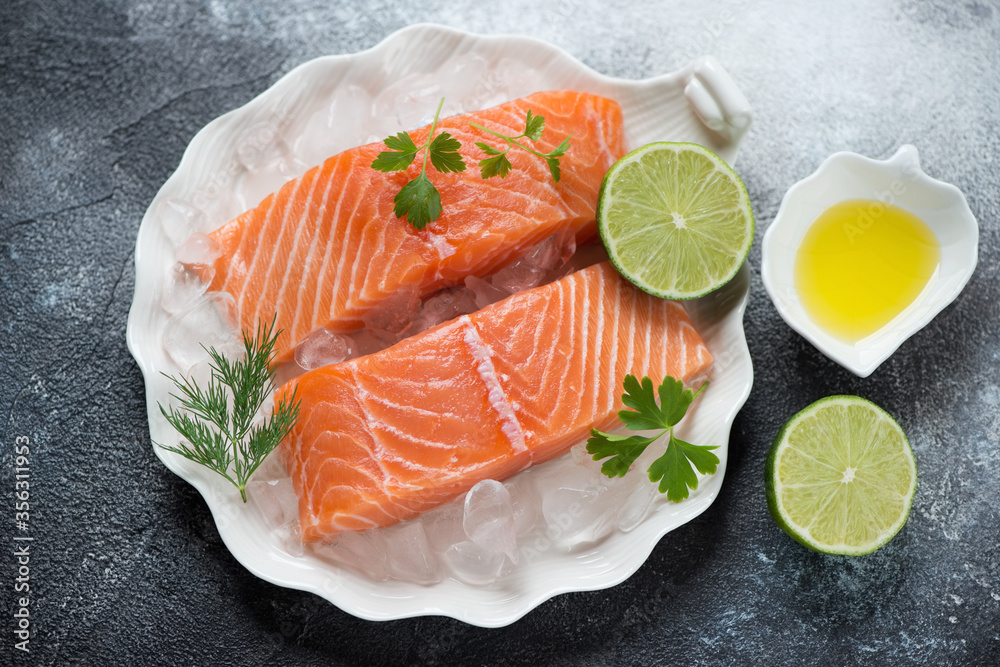 Shell-shaped plate with raw iced salmon fillet and seasonings over dark-grey stone background, horizontal shot Shell-shaped plate with raw iced salmon fillet and seasonings over dark-grey stone background, horizontal shot
