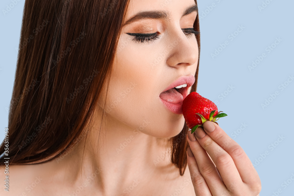 Sexy young woman with strawberry on color background Sexy young woman with strawberry on color background