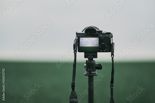 camera on the tripod stands in the field. still photography of nature landscape. modern photo equipment hobby