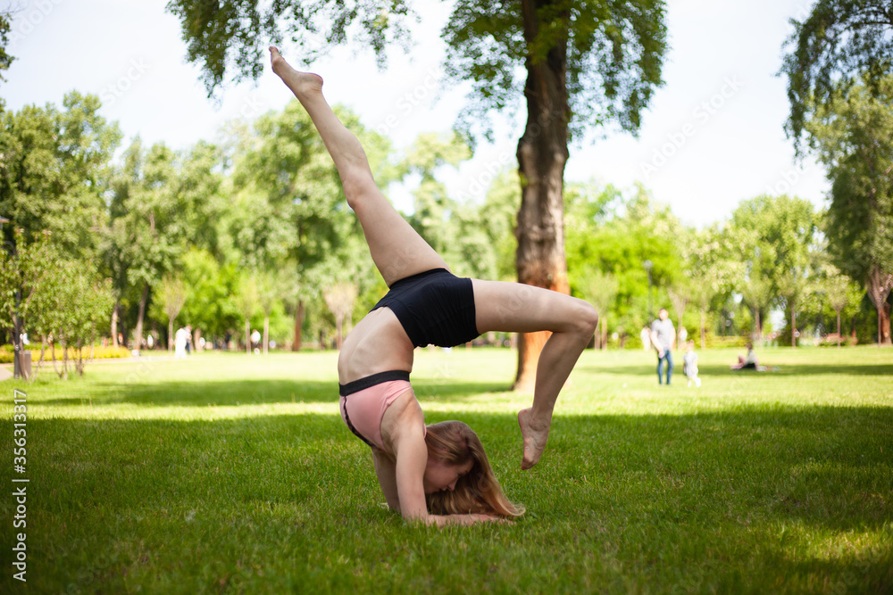 Fototapeta premium Girl is practicing yoga in the park. Healthy lifestyle.