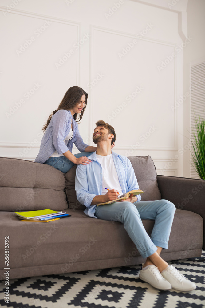 Young man studying before exam and looking at his wife Young man studying before exam and looking at his wife