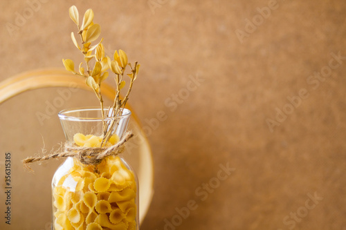 Pasta in a jar, a lot of pasta is scattered around, a jar stands on a wooden stand