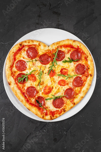 Heart shaped pizza with meat and vegetables. Food concept of romantic love for Valentines Day.