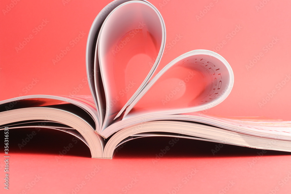 Magazine zu einem Herz geformt mit rotem Hintergrund steht für die Liebe zum Lesen und romanitische Schriften Magazine zu einem Herz geformt mit rotem Hintergrund steht für die Liebe zum Lesen und romanitische Schriften