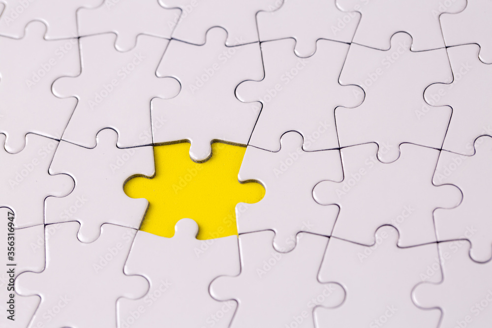 Missing jigsaw puzzle pieces. Business concept. Fragment of a folded white jigsaw puzzle and a pile of uncombed puzzle elements against Missing jigsaw puzzle pieces. Business concept. Fragment of a folded white jigsaw puzzle and a pile of uncombed puzzle elements against