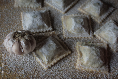 homemade garlic ravioli on wood and loose flour