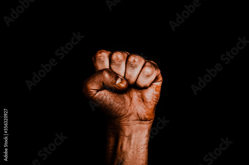 Male black fist on a black background. Aggressiveness, masculinity, the concept of challenge