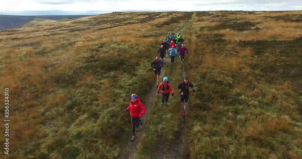 AERIAL WS Group of athletes running in grassy landscape / Yorkshire Moors, Yorkshire, UK