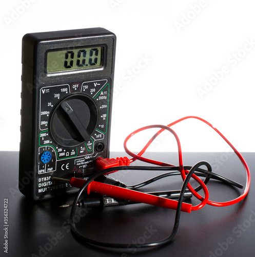 Digital multimeter with probes on a white-black background. close-up.