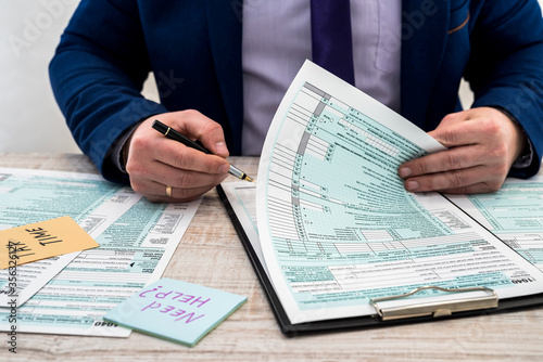 Man in a suit fills out the usa individual 1040 tax form. tax time