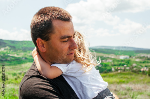 Joyful dad and daughter are playing outdoors in the park. The concept of a happy family. Dad with a baby.