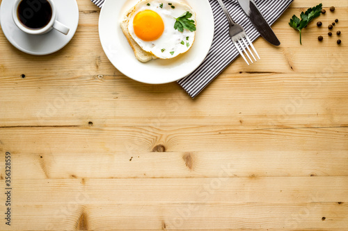 Fried eggs sandwich on plate - light wooden background top-down copy space